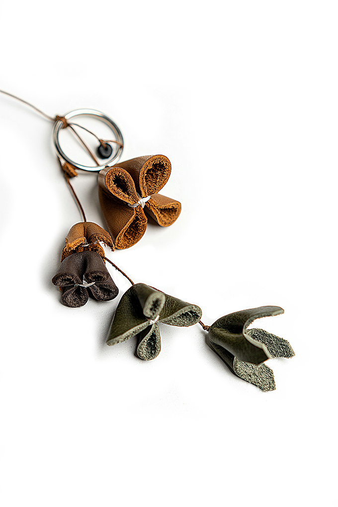 Bag charm showing olive green, beige and purple flowers